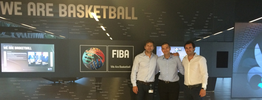 Simon Licĕn and two other standing in front of FIBA we are basketball logo in Switzerland